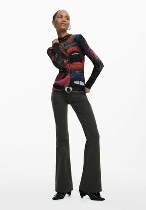 Long-sleeve top with colorful lip prints, paired with dark flared jeans featuring contrasting stitching and a heart-shaped belt buckle.