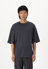 Mørkegrå oversized t-shirt med rund halsudskæring og korte ærmer. Blød bomuldsstoff med en glat tekstur og afslappet pasform.