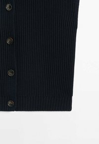 Laivastonsininen ribbineulottu neuletakki, jossa on kuusi pyöreää ruskeaa nappia, teksturoitu neulekuvio ja suora helma.