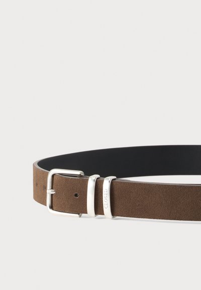 Ceinture en daim marron avec boucle argentée et deux passants, dont un gravé du mot "CLOSED," sur un fond clair uni.