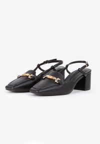Czarne skórzane buty typu slingback z zakończeniem w szpic, z przodu z detalem w postaci złotego łańcucha i na słupku. Gładka tekstura i minimalistyczny design.