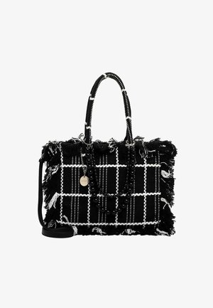 Borsa intrecciata in bianco e nero con bordi sfilacciati, dotata di tracolla con perline e di un'etichetta rotonda in argento. Forma rettangolare strutturata.