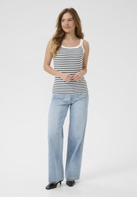 Striped tank top in black and white, paired with light blue wide-leg jeans and black heeled shoes. Smooth fabric and casual fit.
