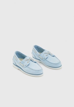 Zapatos de barco de ante azul claro con suelas de goma blanca, costuras detalladas y ojetes plateados, que presentan un diseño clásico de cordones.