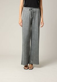 Grijze wijde broeken met een glanzende afwerking, voorzien van een elastische tailleband en een verstelbaar trekkoord, gecombineerd met zwarte sandalen met bandjes.