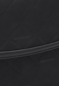 Borsa a tracolla nera trapuntata con finitura testurizzata, bordi in pelle liscia e logo "Valentino" impresso sulla superficie.