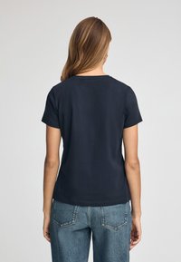 Camiseta de manga corta azul marino con cuello redondo, hecha de una tela suave. Presenta un corte recto y un diseño de espalda sin costuras.