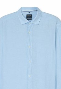 Camicia button-up azzurro chiaro realizzata in tessuto testurizzato; presenta un colletto, una tasca sul petto e bottoni bianchi lungo il davanti. Design a vestibilità regolare.