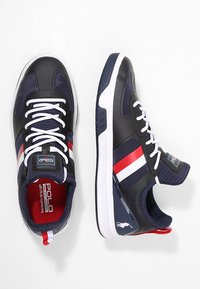 Laivastonsiniset urheilukengät, joissa on verkkokangas, valkoiset nauhat ja punaiset/valkoiset raidat. Varusteena pehmustettu pohja ja logotieto.