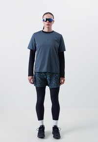 Sportlik riietus, mis koosneb hallist lühikese varrukaga särgist, mustast pika varrukaga kihist, mustritest sinistest lühikeste pükstest, mustadest leggingutest ja prillidest.