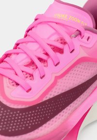 Buty biegowe Nike Zoom Fly, z warstwowym wzorem w różnych odcieniach różowego, posiadają teksturowaną powierzchnię oraz oddychające akcenty z siateczki.