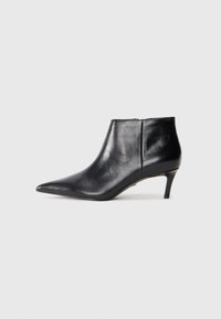 Botte de cheville en cuir noir avec un bout pointu et un talon moyen élancé, présentée en profil latéral sur fond blanc.