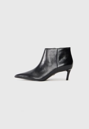 Botte de cheville en cuir noir avec un bout pointu et un talon moyen élancé, présentée en profil latéral sur fond blanc.