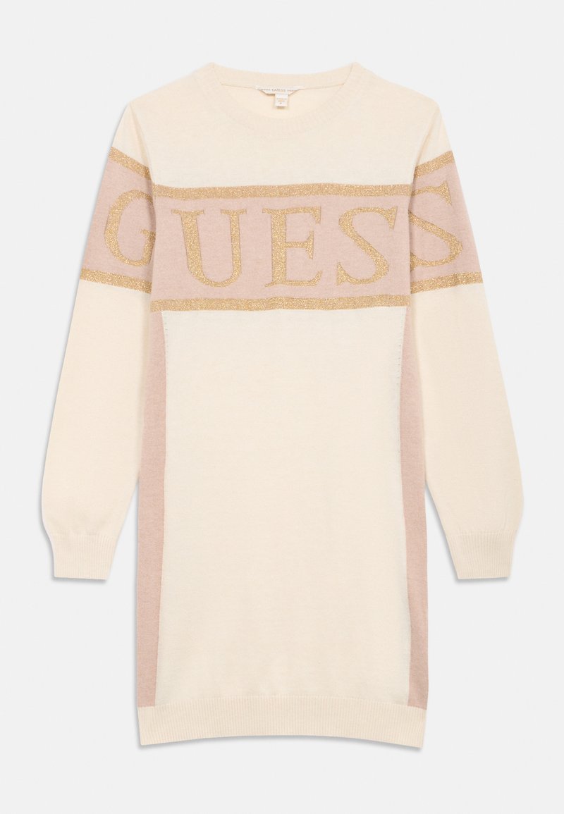 Pletené svetrové šaty v krémové barvě s bledě růžovými bočními panely. Na hrudi se nachází zlatý třpytivý logotyp "GUESS". Dlouhé rukávy, kulatý výstřih.