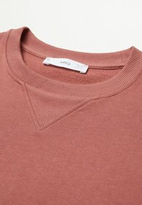 Różowa bluza z prążkowanym, zaokrąglonym dekoltem i detalem przeszycia na ramieniu. Gładka tekstura z miękkim, casualowym stylem.