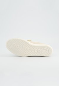 Semelle de basket beige avec une texture antidérapante et "Paul Green" embossé sur la semelle en caoutchouc blanc, sur un fond uni.