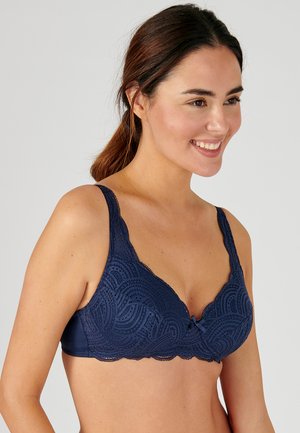 Reggiseno in pizzo blu navy con bordi scallop e un motivo floreale. Presenta spalline regolabili e un piccolo fiocco al centro.