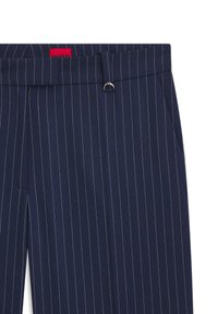 Pantalon bleu marine à fines rayures blanches, doté d'une passoire à ceinture avec un accent métallique, de poches latérales et d'une fermeture éclair. Texture de tissu lisse.