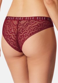 Bordeauxrode kanten slipjes met een luipaardpatroon, voorzien van een brede elastische tailleband met "ELLE" erin verwerkt. Fijne en halfdoorzichtige textuur.