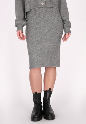 Grauer gerippter Strick-Pencilskirt mit einem dezenten Saum, kombiniert mit schwarzen Leder-Ankle-Boots mit dicken Sohlen und Zuglaschen.