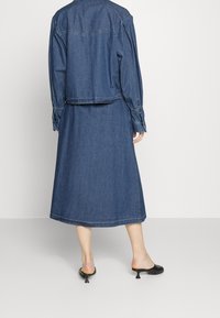 Denimoutfit som har en kort jacka med puffärmar och en lång kjol. Färg: mörkblå. Pricken över i:et med enkel söm och en avslappnad passform.