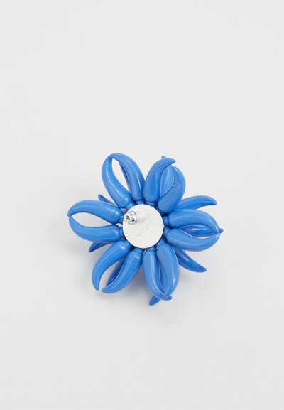 Broche floral azul hecha de plástico con formas de pétalos alargadas, que cuenta con un centro plateado y una textura suave.