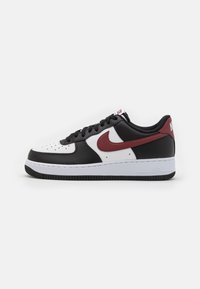 Baskets en cuir noir et blanc avec un swoosh rouge de Nike, bout arrondi, détails perforés et semelle en caoutchouc blanc.