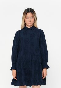 Navy blue dress made from textured fabric with floral embroidery, featuring a button-down front, collar, and long puffed sleeves.