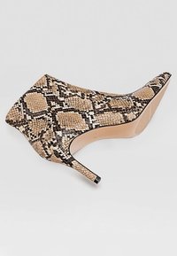 Décolleté in finta pelle di serpente con motivo beige, nero e bianco. Presenta un elegante tacco a stiletto e una superficie texturizzata.