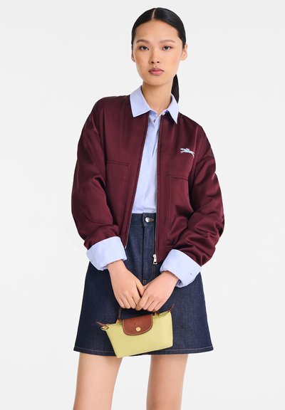 Burgundy satin bomber jacket with ribbed cuffs, light blue collared shirt, denim skirt, and a small yellow bag with brown accents.