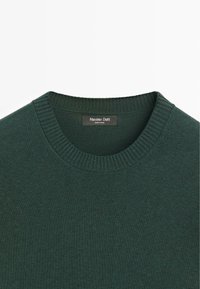 Maglione verde lavorato a maglia con scollo rotondo a coste. Presenta una texture morbida e un design semplice. Etichetta visibile: Massimo Dutti, made in China.