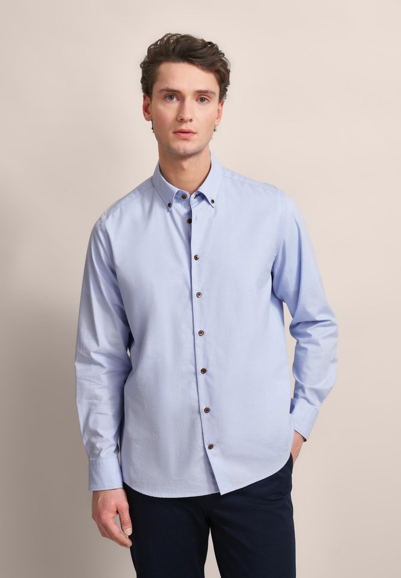 Hellblaues Button-up-Hemd mit langen Ärmeln, das braune Knöpfe und einen Kragen hat. Hergestellt aus glattem Stoff mit lockerer Passform.