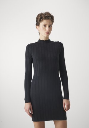 Zwarte ribgebreide jurk met lange mouwen en een gegolfde halslijn. Slim fit, knie-lang, met zichtbare textuurdetails in de stof.