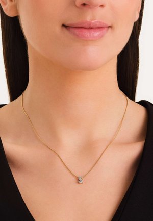 Collar de oro con una cadena delgada y un pequeño colgante brillante en forma de letra, adornado con diamantes transparentes.