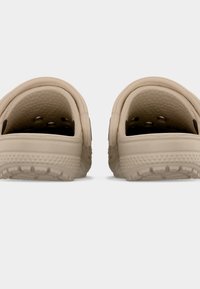 Ζευγάρι μπεζ παπούτσια τύπου clogs χωρίς κορδόνια με υφασμένους πάτους και οπές αερισμού, ορατά από πίσω σε απλό λευκό φόντο.