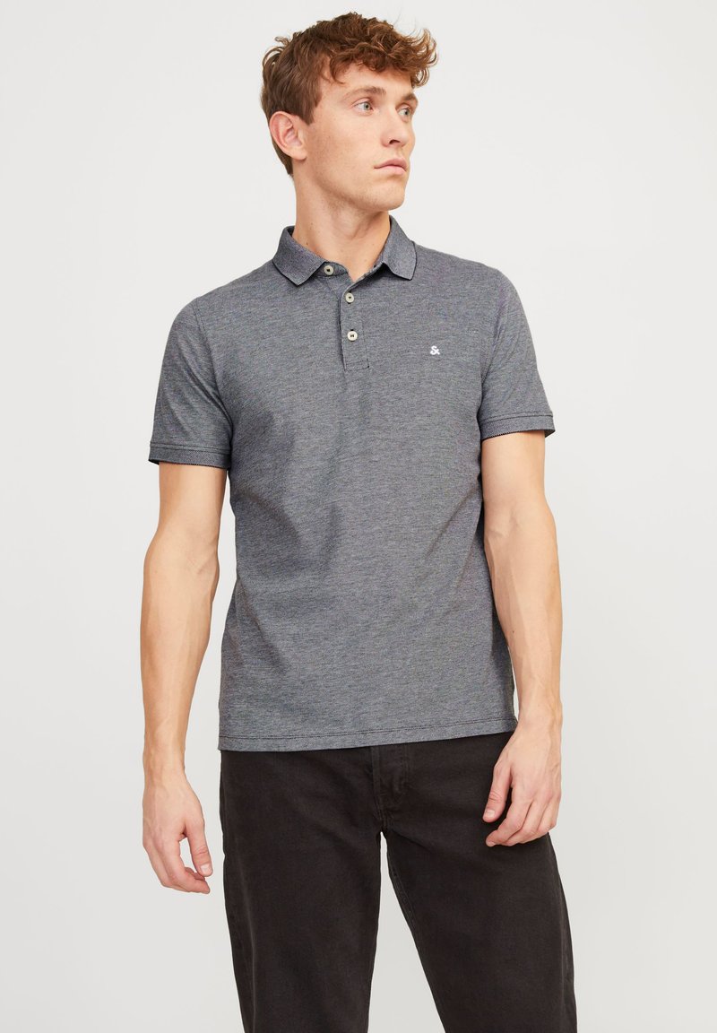 Gray polo shirt with a collared neck, featuring three buttons and short sleeves. The fabric has a textured finish and a small logo.