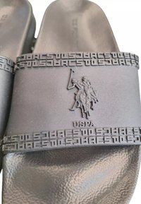 Infradito in gomma nera con pedana testurizzata, logo in rilievo di un cavaliere e fascetta decorata con la scritta "USPA".