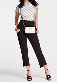 T-shirt grigio con strisce bianche, pantaloni neri sagomati con orlo corto e una piccola borsa a tracolla crema. Tacchi neri con cinturini completano l'outfit.