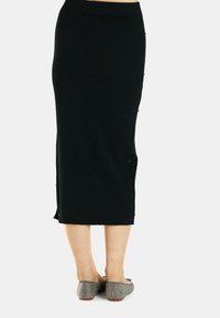 Falda midi negra de canalé con aberturas laterales y botones decorativos. Confeccionada en tejido elástico, presenta una silueta ajustada y cinturilla elástica.