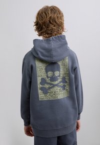 Sudadera gris con un gran gráfico de calavera y huesos cruzados en la parte trasera, que presenta patrones de texto. Material de algodón, diseño tipo pullover.