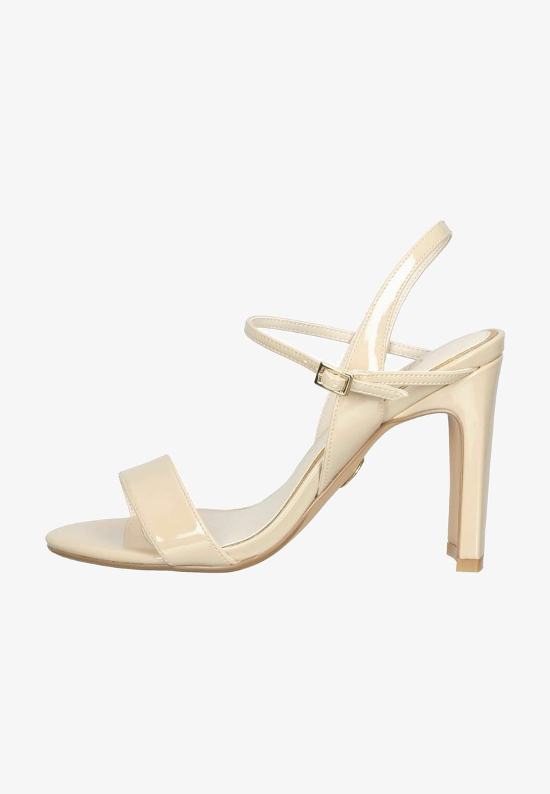 Μπεζ παπούτσι με ψηλό τακούνι από λουστρίνι, ανοιχτή μύτη, δύο λουράκια κατά μήκος του ποδιού και λεπτό λουράκι αστραγάλου με χρυσή αγκράφα.