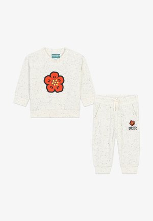 Sweatshirt blanc avec des taches et joggers assortis. Présente une grande broderie de fleur rouge sur la poitrine et sur le côté, avec le texte "KENZO PARIS".