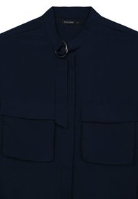 Navy blue blouse featuring a stand collar, two front pockets, a toggle closure, and a smooth fabric texture. Brand label: Calliope, size S.