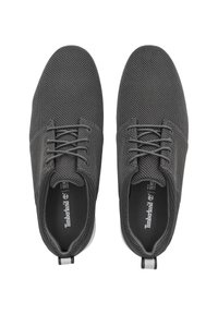 Gray mesh sneakers with a textured surface, featuring black laces, a cushioned insole, and a white rubber sole. Timberland logo on the tongue.