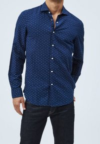 Laivastonsininen pitkähihaisen paidan, jossa on nappikiinnitteinen kaulus, hillitty pilkkukuosi, edessä napit ja sileä kangaspinta.