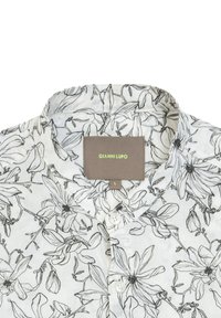 Camicia bianca con motivo floreale nero, colletto corto e apertura con bottoni. L'etichetta riporta "GIANNI LUPO", taglia L. La texture sembra leggera.