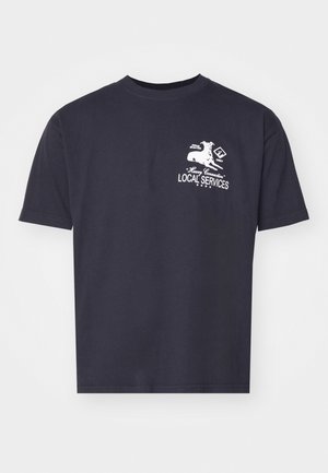 Tricou din bumbac de culoare bleumarin, cu mâneci scurte, având imprimeu grafic alb cu un câine și textul "SERVICII LOCALE" pe față.