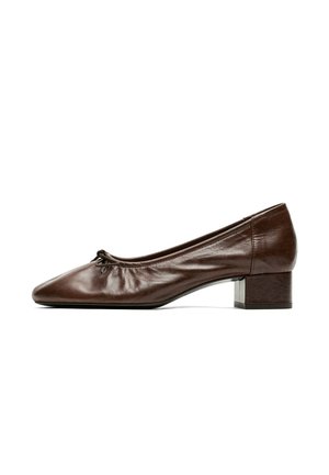 Scarpa da donna in pelle marrone con tacco basso, punta arrotondata e piccolo dettaglio con fiocco nella parte anteriore, vista di lato su sfondo bianco.