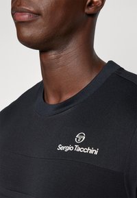 Czarny koszulka sportowa z ribbowanym dekoltem, z białym logo Sergio Tacchini na klatce piersiowej i teksturowanymi poziomymi liniami na tkaninie.