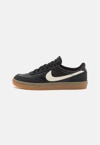 Baskets noires en cuir et suède, avec un logo swoosh blanc et une semelle en caoutchouc gum ; bout rond et design à lacets.
